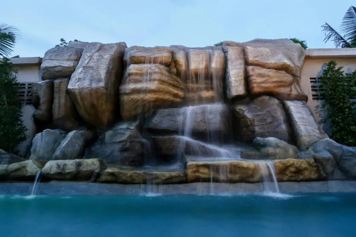 Artificial Rock Waterfall Feature with Clear Blue Pool and Greenery in Phuket Town