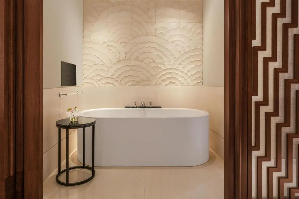 Bathroom Area with Freestanding Bathtub and Textured Tile Wall Near City Hall