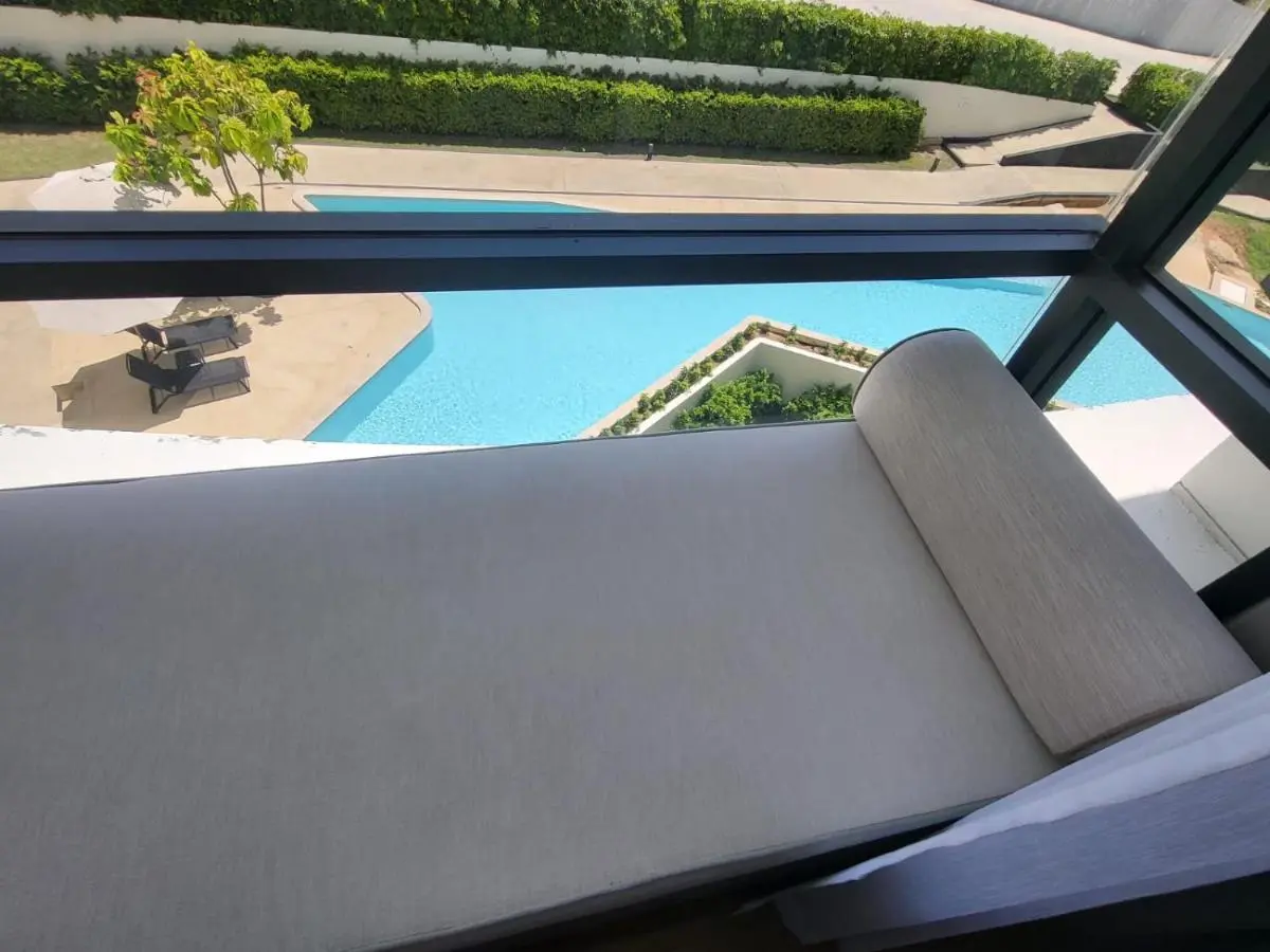 Indoor Seating Overlooking Geometric Outdoor Pool with Lounge Chairs and Umbrella at Rawai Beach