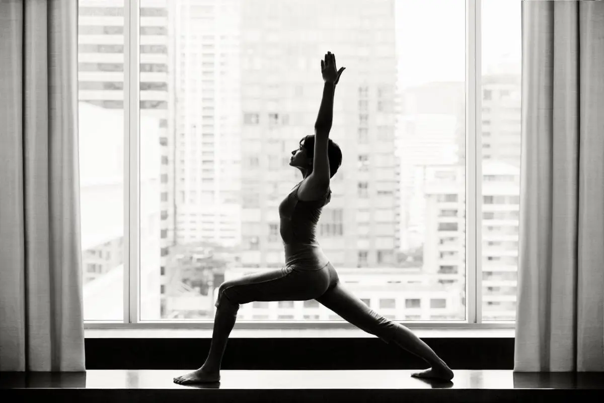 Indoor Yoga Lunge Pose with Urban Cityscape View in Sathorn High-Rise Apartment