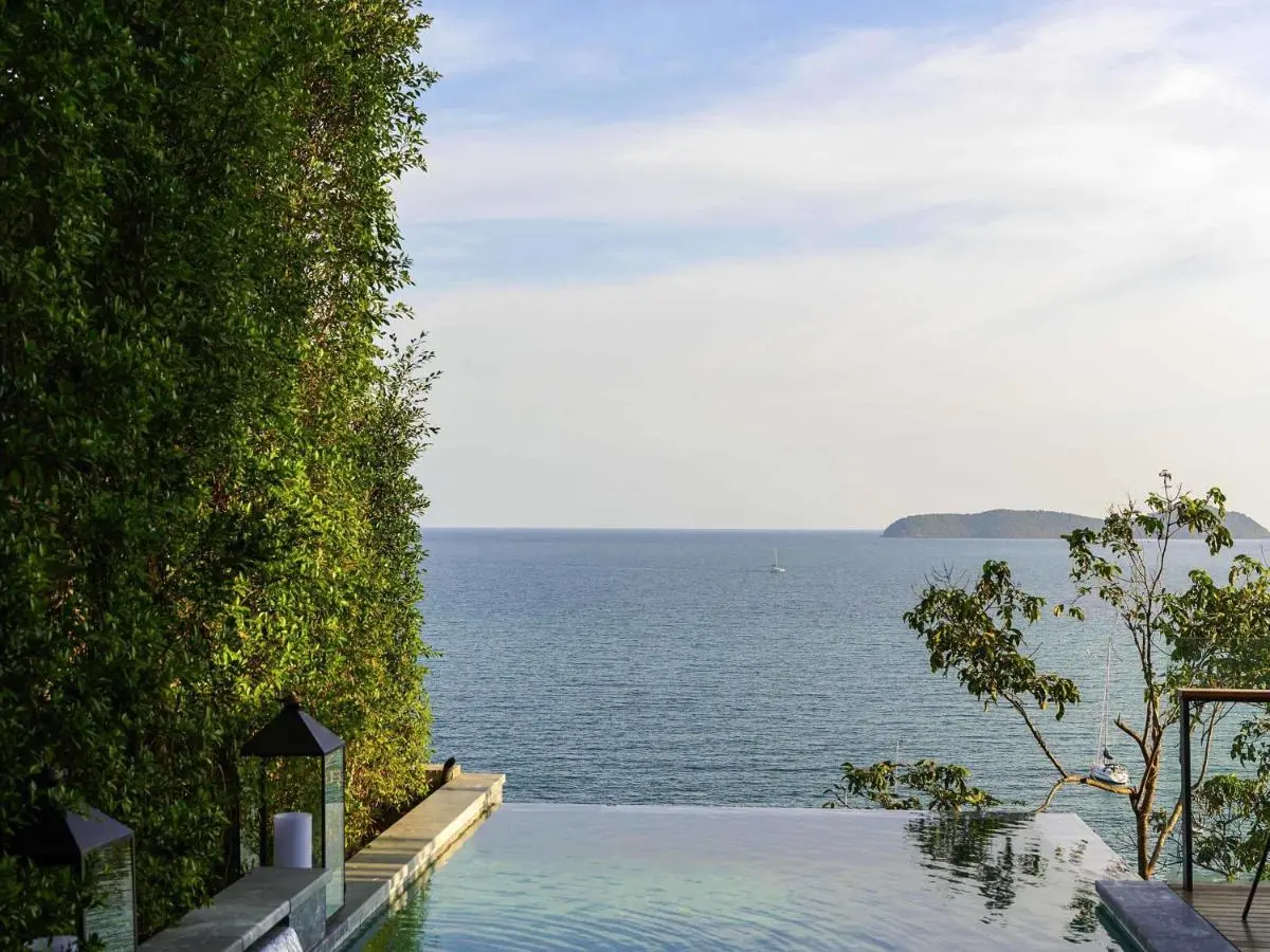 Infinity Pool Overlooking Ocean with Green Wall and Sailboats at Panwa Beach