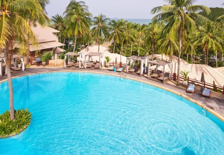 Large Circular Outdoor Swimming Pool with Lounge Chairs and Ocean Views at Panwa Beach