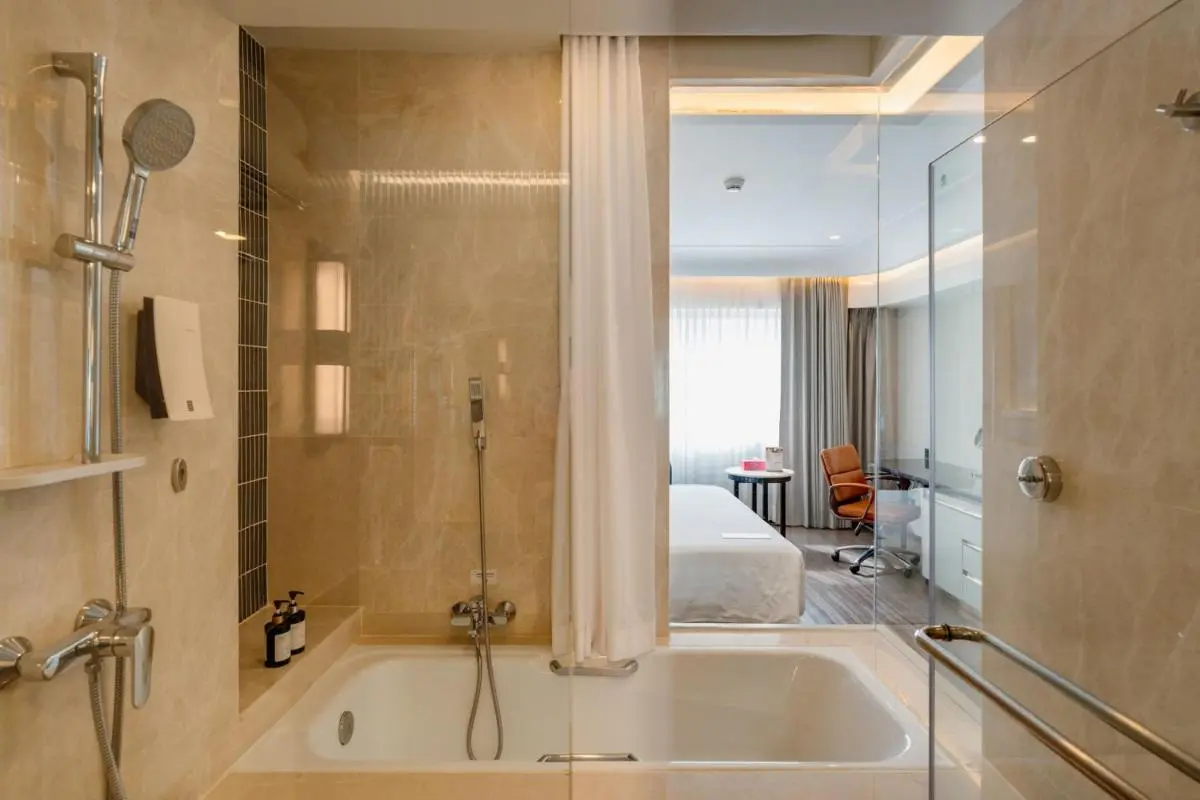 Ramada Plaza by Wyndham Bangkok Menam Riverside Modern Bathroom and Bedroom Interior with Bathtub and Glass Partition in Bang Kho Laem