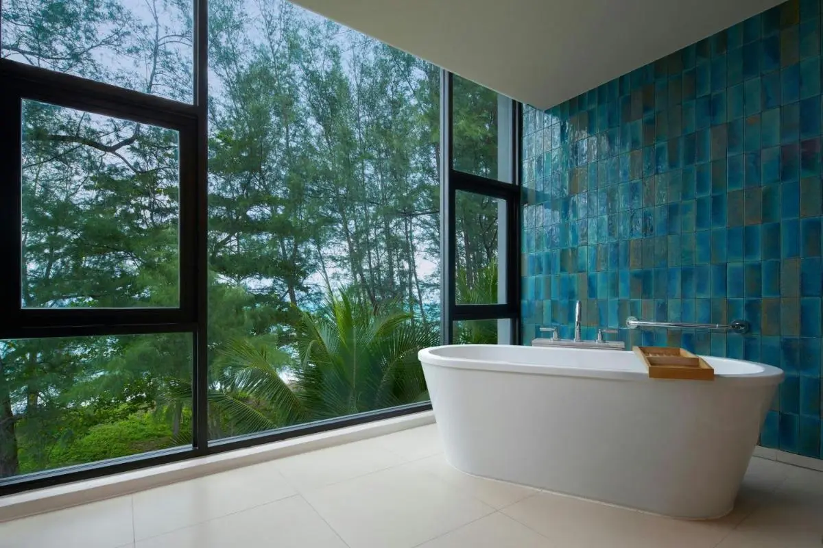 Modern Bathroom with Freestanding Bathtub and Large Windows Overlooking Tropical Foliage