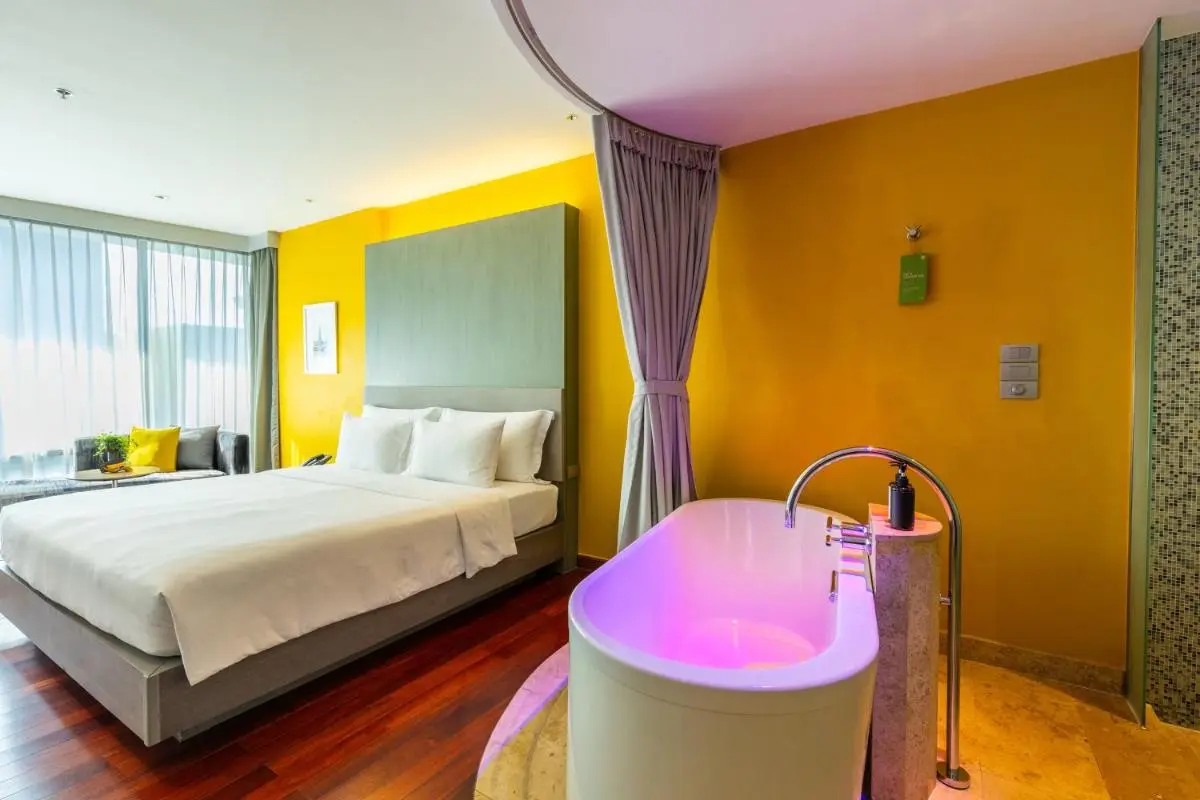 LiT BANGKOK Hotel Modern Bedroom with Integrated Illuminated Bathtub and Seating Area in Pathumwan