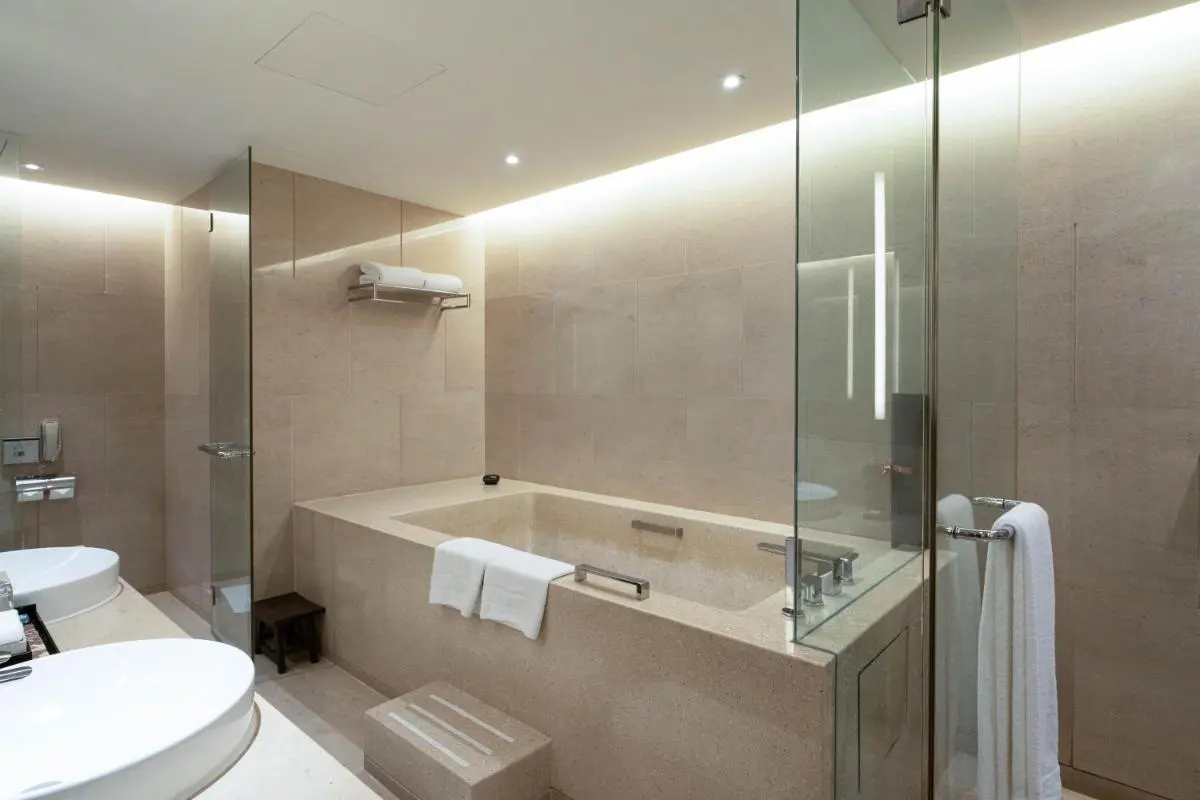 Modern Beige Tiled Bathroom with Built-In Bathtub and Glass Partition in Pathumwan