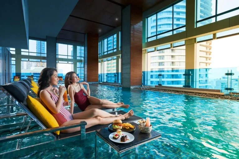 Modern Indoor Pool Area with Lounge Seating and Urban Views in Pathumwan Bangkok