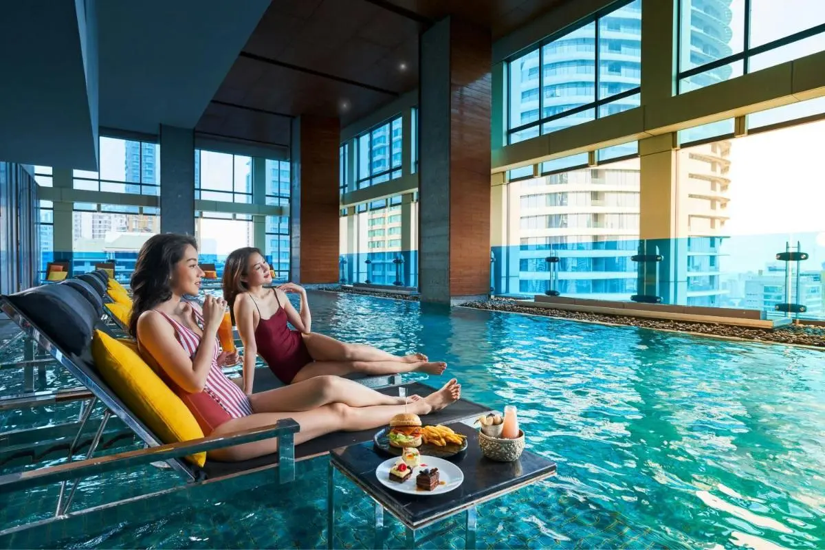 Modern Indoor Pool Area with Lounge Seating and Urban Views in Pathumwan Bangkok