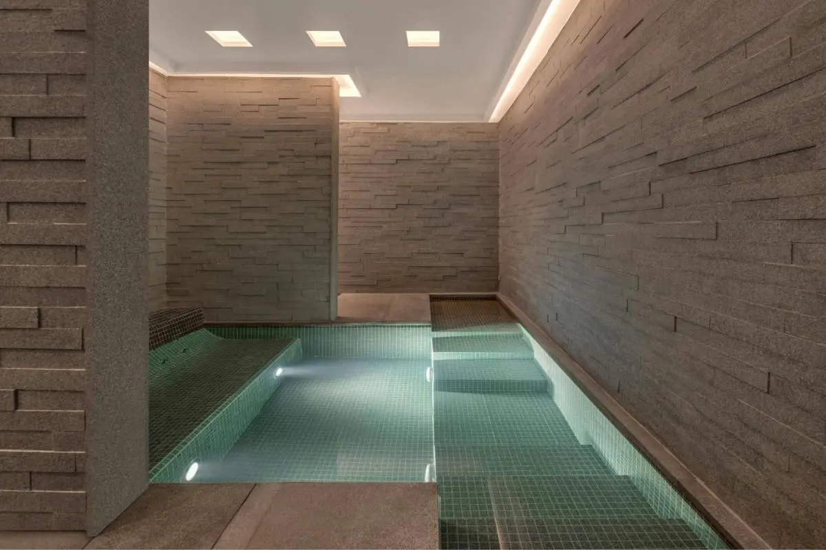 Modern Indoor Pool Area with Stone Walls and Ambient Lighting in Pathumwan Bangkok