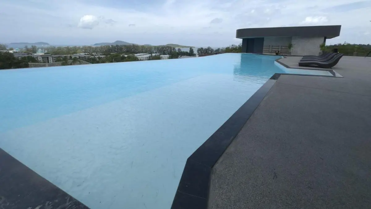 Modern Outdoor Infinity Pool with Lounge Chairs Overlooking Coastal View at Rawai Beach