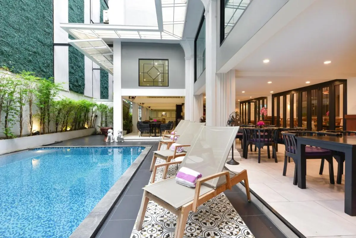 Modern Outdoor Pool Area with Lounge Chairs and Green Wall in Phra Nakhon Courtyard