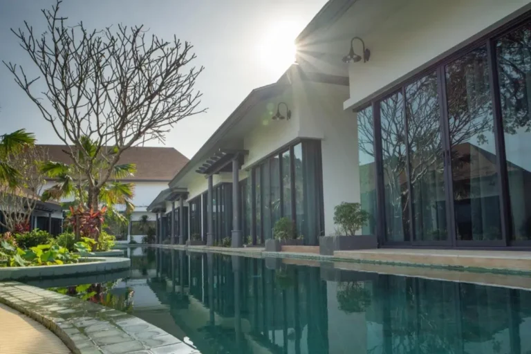 Modern Outdoor Rectangular Pool with Tranquil Landscaping and Glass Facade in Chalong
