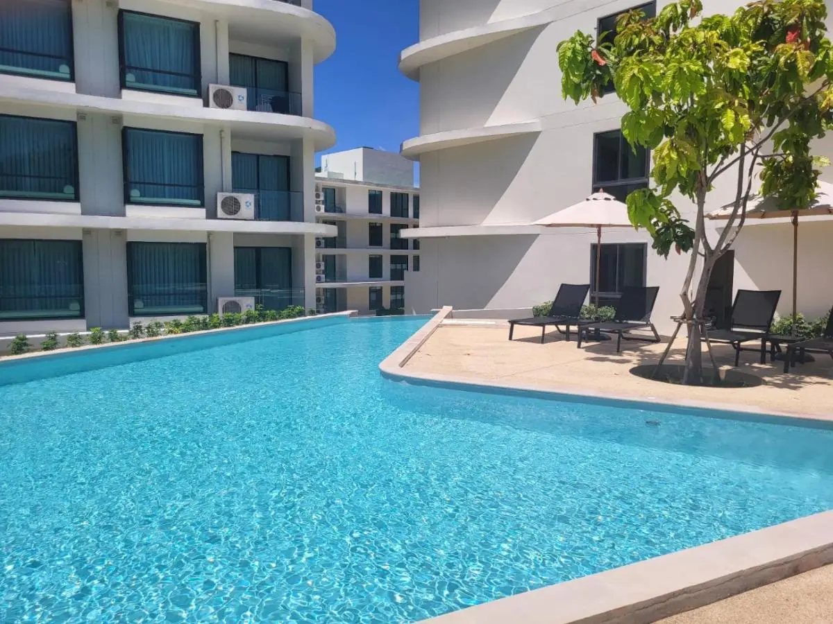 Modern Outdoor Swimming Pool Area with Lounge Chairs and Umbrellas at Rawai Beach