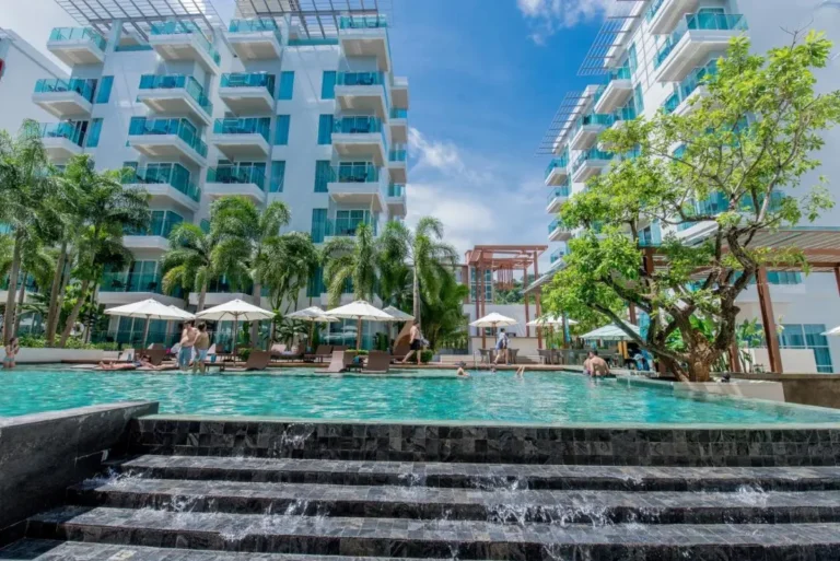Modern Outdoor Swimming Pool Area with Waterfall and Lounge Seating at Patong Beach