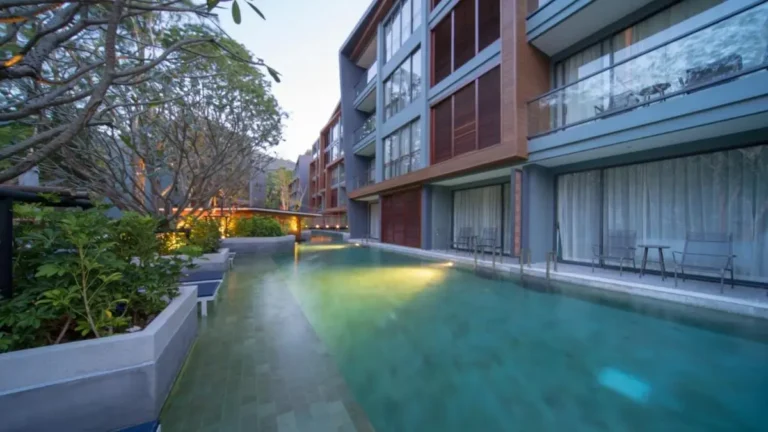 Modern Outdoor Swimming Pool with Lounge Area and Glass-Fronted Building Near Patong Beach