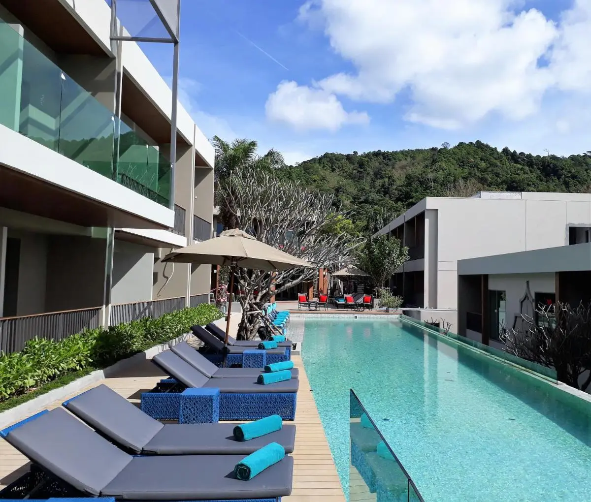 Modern Outdoor Swimming Pool with Lounge Area and Scenic Forested Hills at Patong Beach