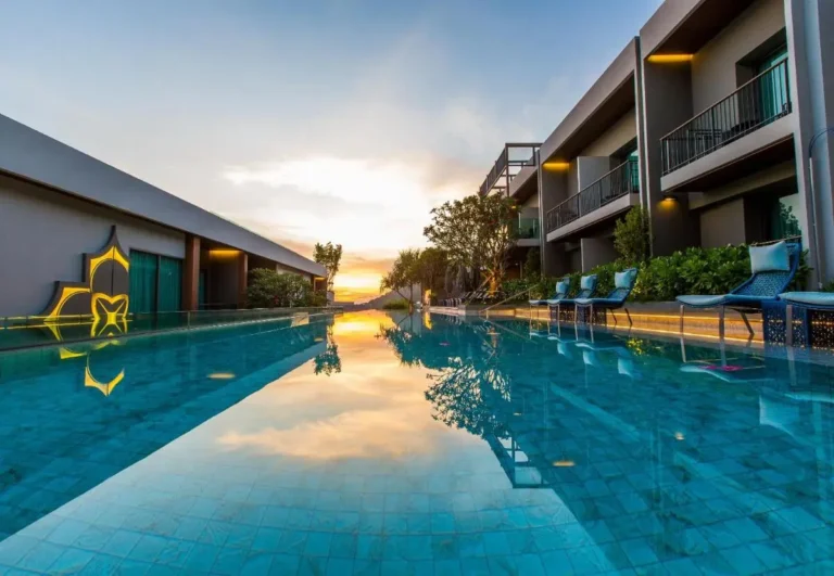 Modern Outdoor Swimming Pool with Lounge Chairs and Sunset View at Patong Beach