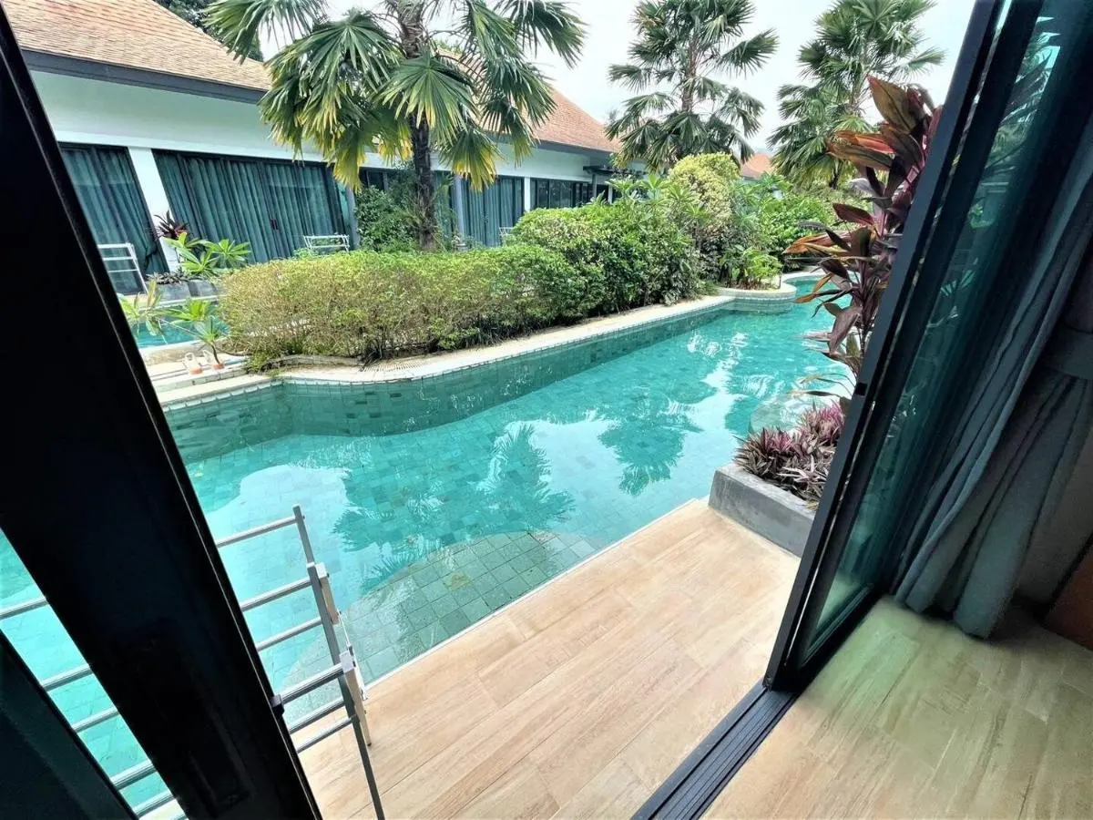 Narrow Elongated Swimming Pool with Tropical Landscaping and Glass Doors in Chalong