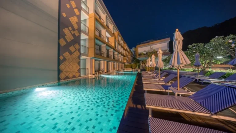 Nighttime View of Outdoor Swimming Pool with Lounge Chairs and Wooden Deck at Patong Beach