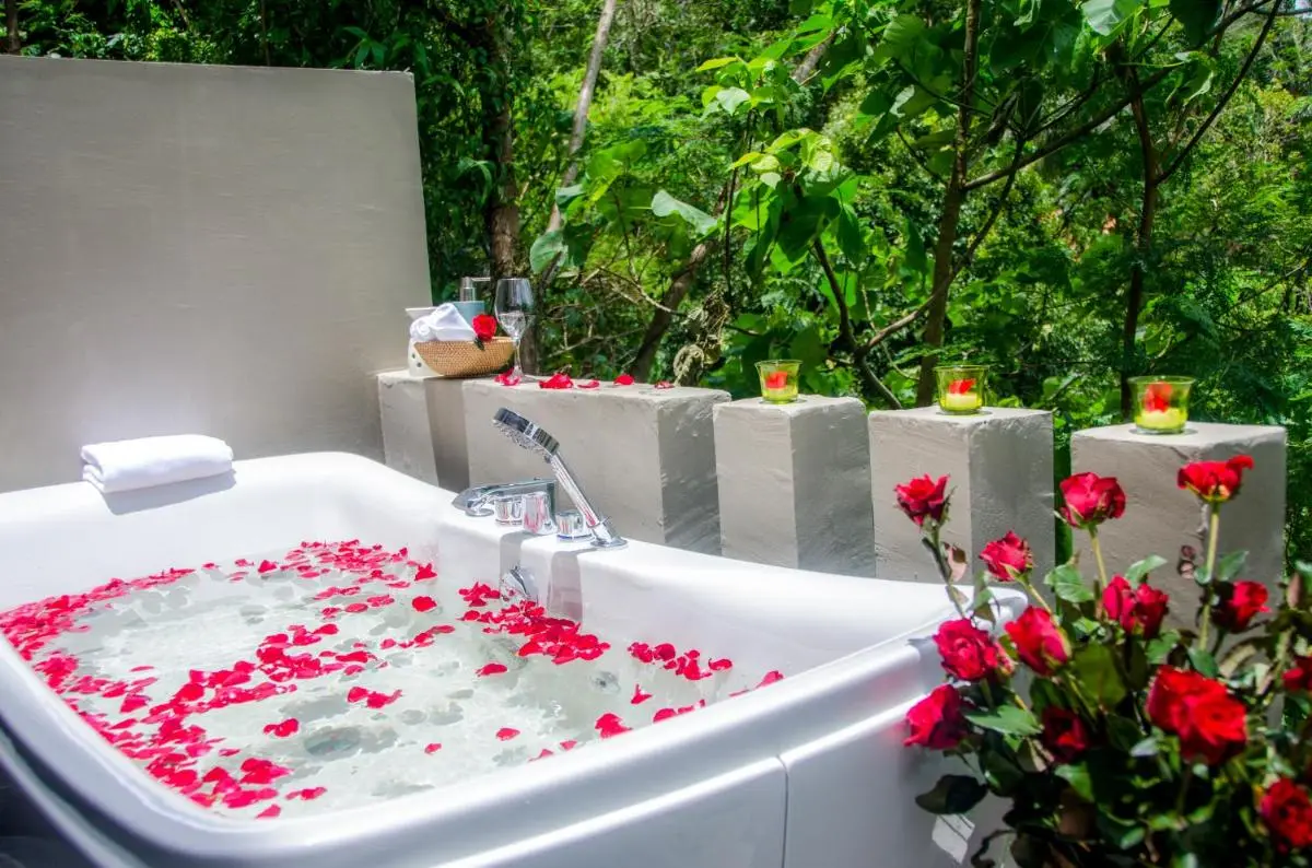 Outdoor Bathtub with Rose Petals and Candlelit Pedestals in Natural Setting at Patong Beach