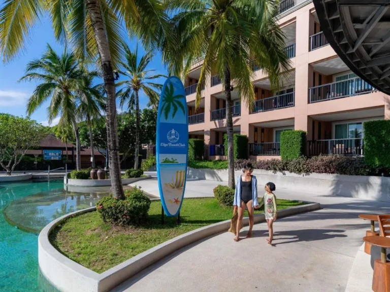 Outdoor Curved Pool Area with Palm Trees and Adjacent Multi-Story Building at Panwa Beach