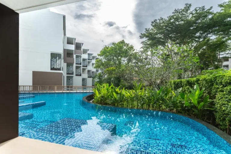 Outdoor Curved Swimming Pool with Blue Mosaic Tiles and Lush Greenery at Mai Khao Beach