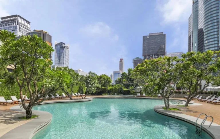 Outdoor Freeform Swimming Pool with Lounge Chairs and Urban Skyline in Pathumwan Bangkok