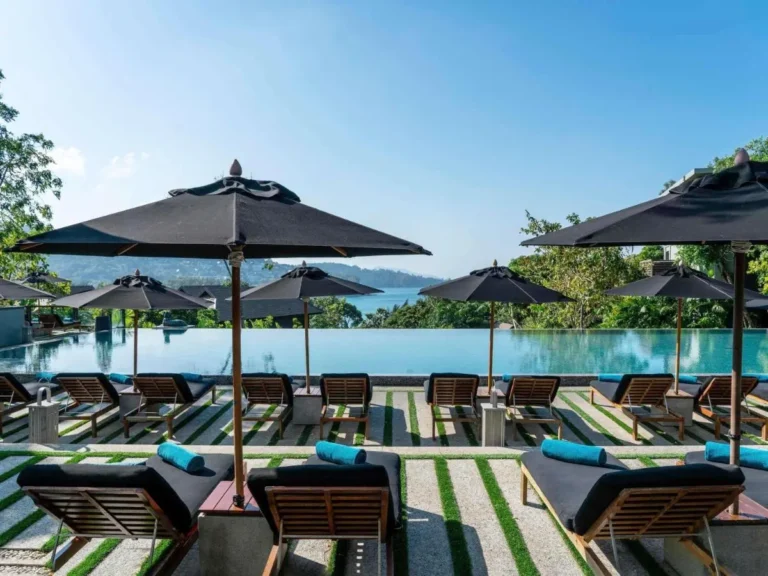 Outdoor Infinity Pool Overlooking Nai Thon Beach with Lounge Chairs and Umbrellas