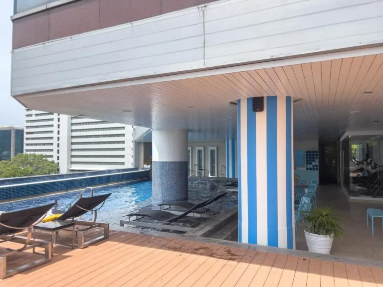Outdoor Pool Area with Lounge Chairs and Indoor Fitness Space in Bang Rak Bangkok