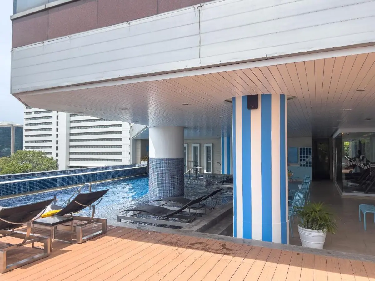 Outdoor Pool Area with Lounge Chairs and Indoor Fitness Space in Bang Rak Bangkok