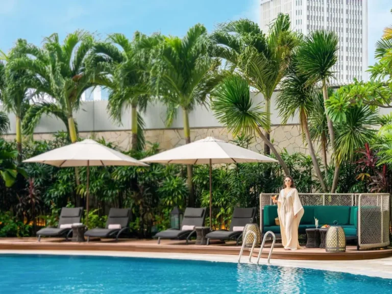 Outdoor Pool Area with Lounge Chairs and Tropical Plants Near City Hall