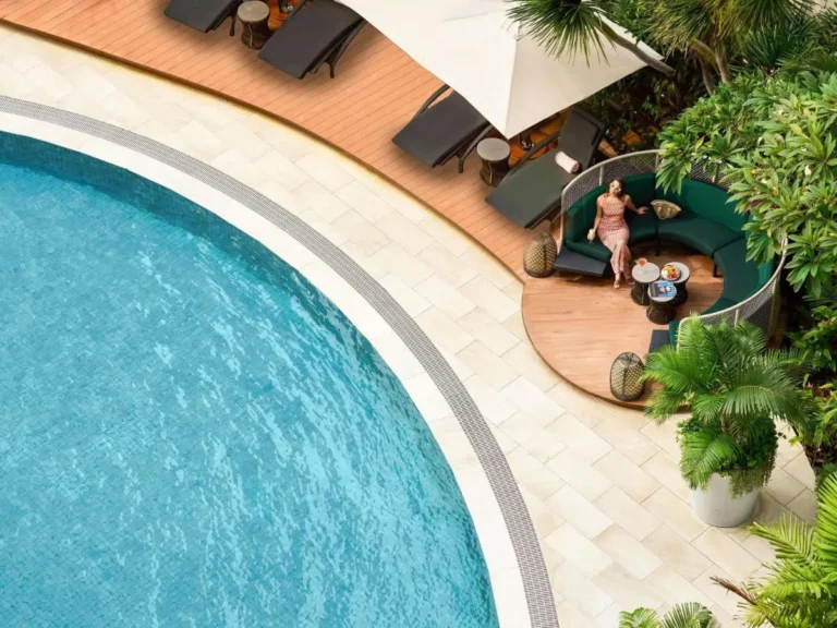 Outdoor Pool Area with Lounge Seating and Tropical Plants Near City Hall