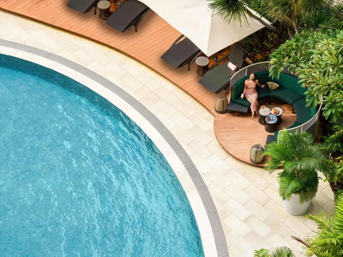 Outdoor Pool Area with Lounge Seating and Tropical Plants Near City Hall