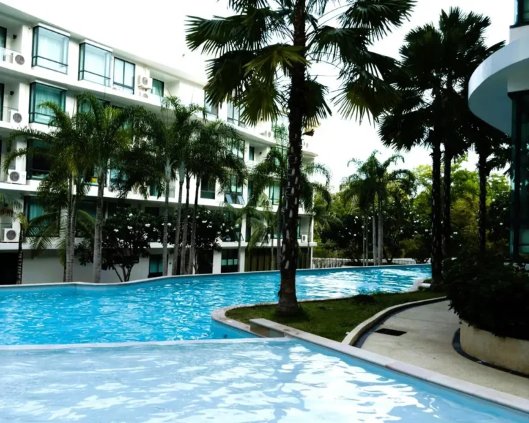 Outdoor Pool Area with Palm Trees and Multi-Story Building at Rawai Beach