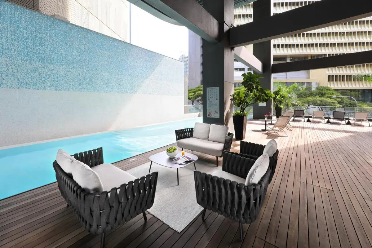 Outdoor Pool Area with Seating and Lounge Chairs on Wooden Deck in Singapore