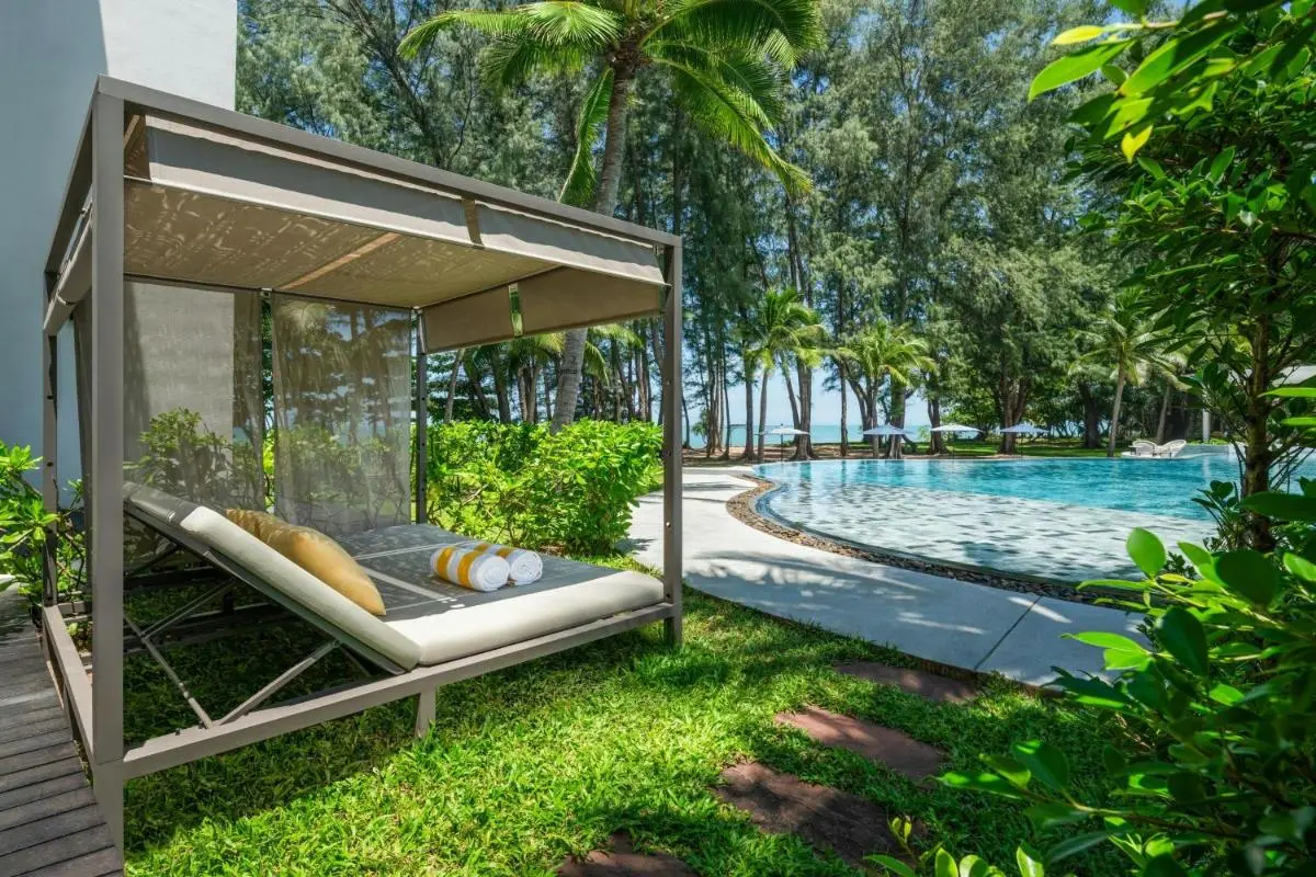Outdoor Pool Area with Shaded Daybed and Lounge Chairs Near Mai Khao Beach