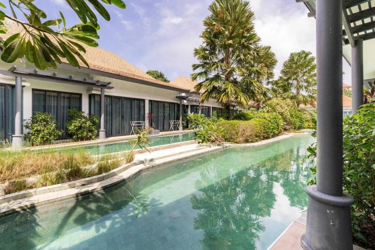 Outdoor Pool Area with Tropical Vegetation and Glass-Fronted Building in Chalong