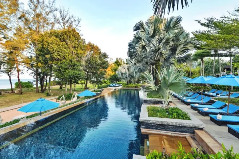 Outdoor Rectangular Swimming Pool with Blue Lounge Chairs and Palm Trees at Mai Khao Beach
