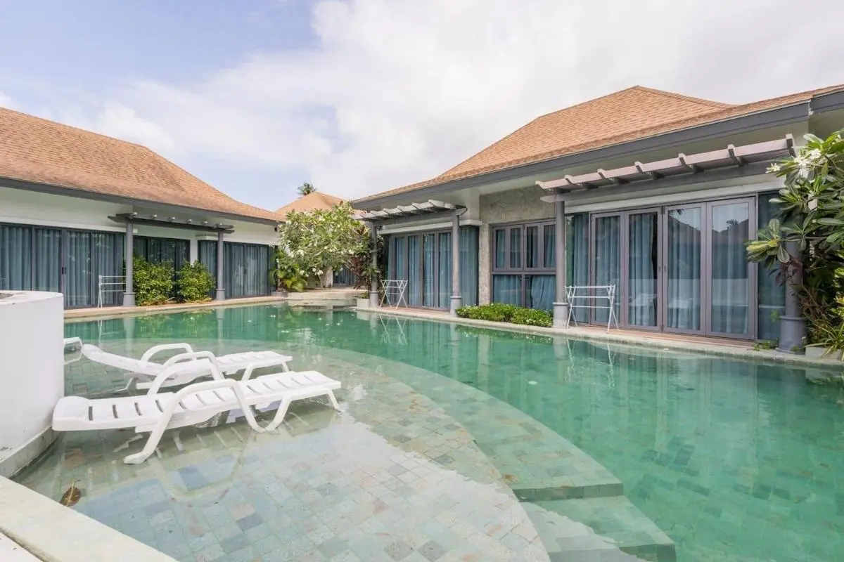 Outdoor Rectangular Swimming Pool with Lounge Chairs and Adjacent Single-Story Buildings in Chalong