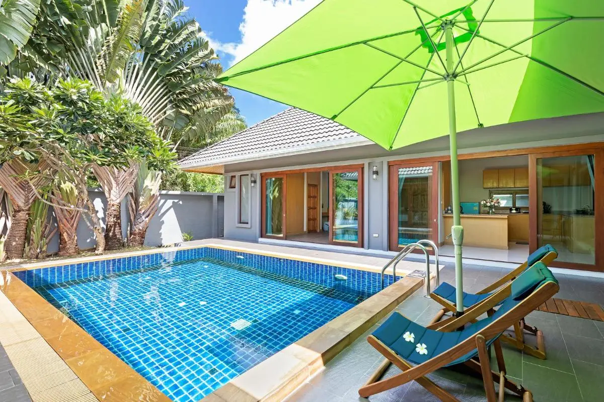 Outdoor Rectangular Swimming Pool with Lounge Chairs and Green Umbrella at Rawai Beach