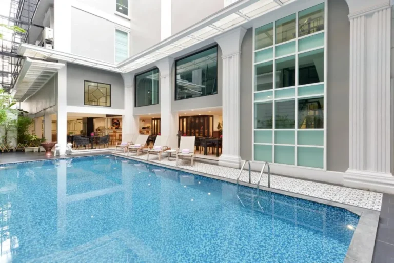 Outdoor Rectangular Swimming Pool with Lounge Chairs and Modern Building in Phra Nakhon
