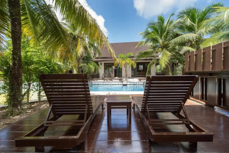 Outdoor Rectangular Swimming Pool with Wooden Lounge Chairs and Tropical Surroundings in Thalang