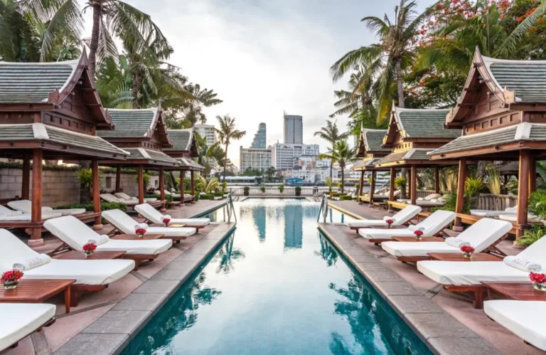 Outdoor Swimming Pool and Relaxation Area with Cabanas and Waterfront View in Khlong San Bangkok
