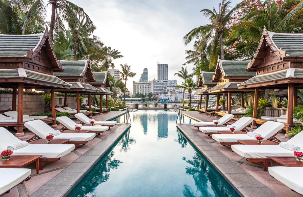 Outdoor Swimming Pool and Relaxation Area with Cabanas and Waterfront View in Khlong San Bangkok