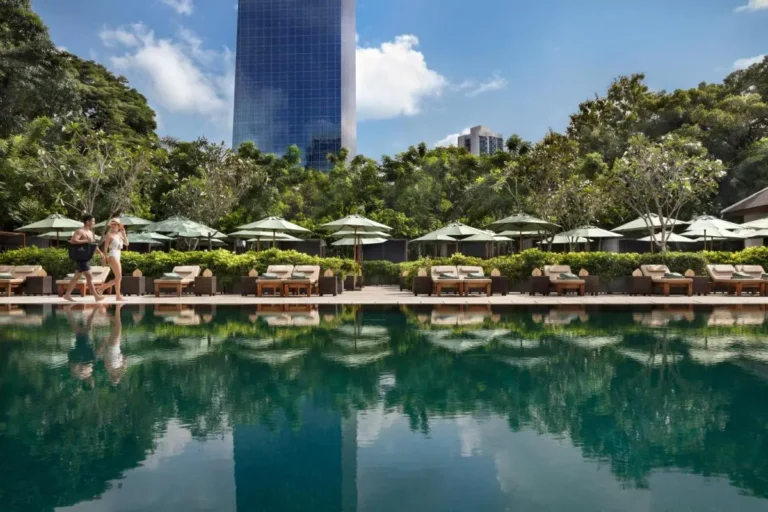 Outdoor Swimming Pool Area with Lounge Chairs and Green Umbrellas in Sathorn Bangkok