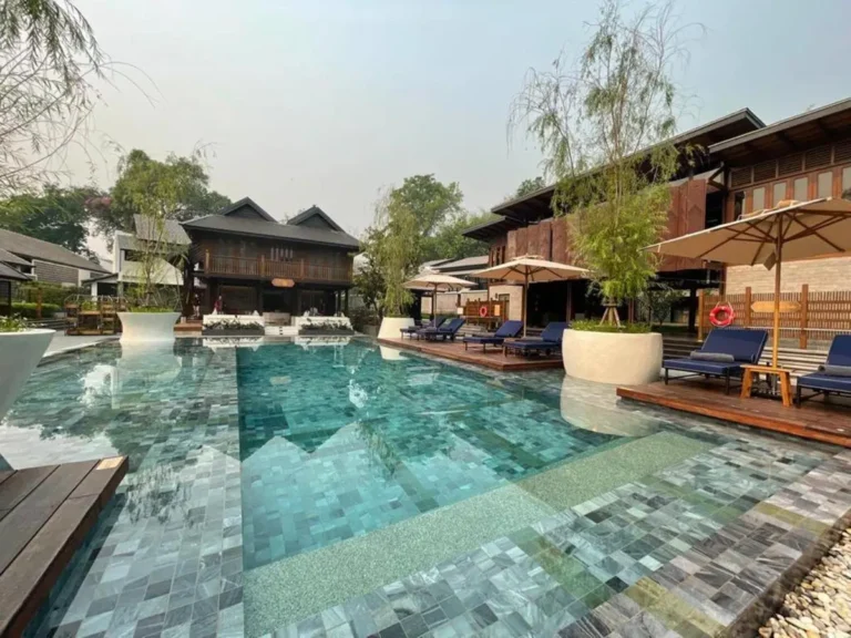 Outdoor Swimming Pool Area with Lounge Chairs and Greenery in Chiang Mai