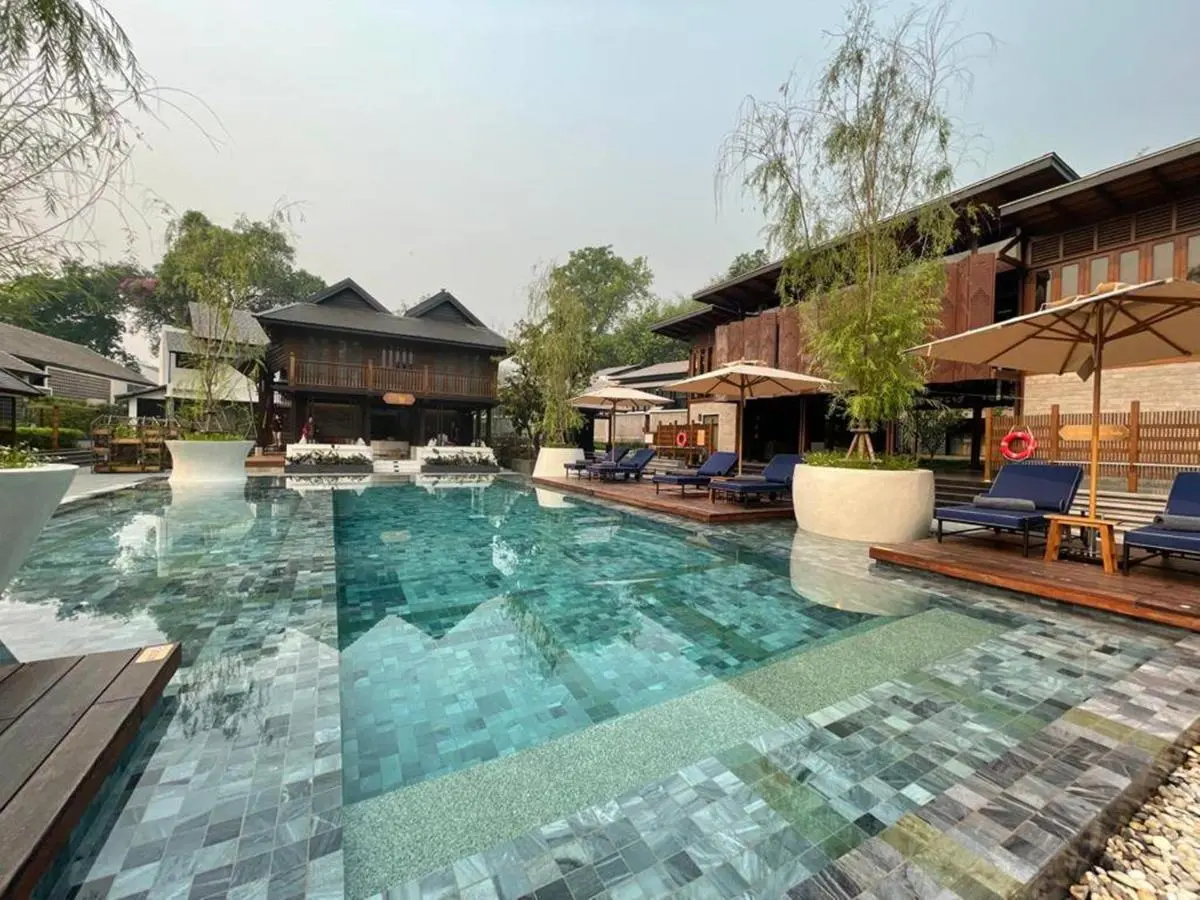 Outdoor Swimming Pool Area with Lounge Chairs and Greenery in Chiang Mai