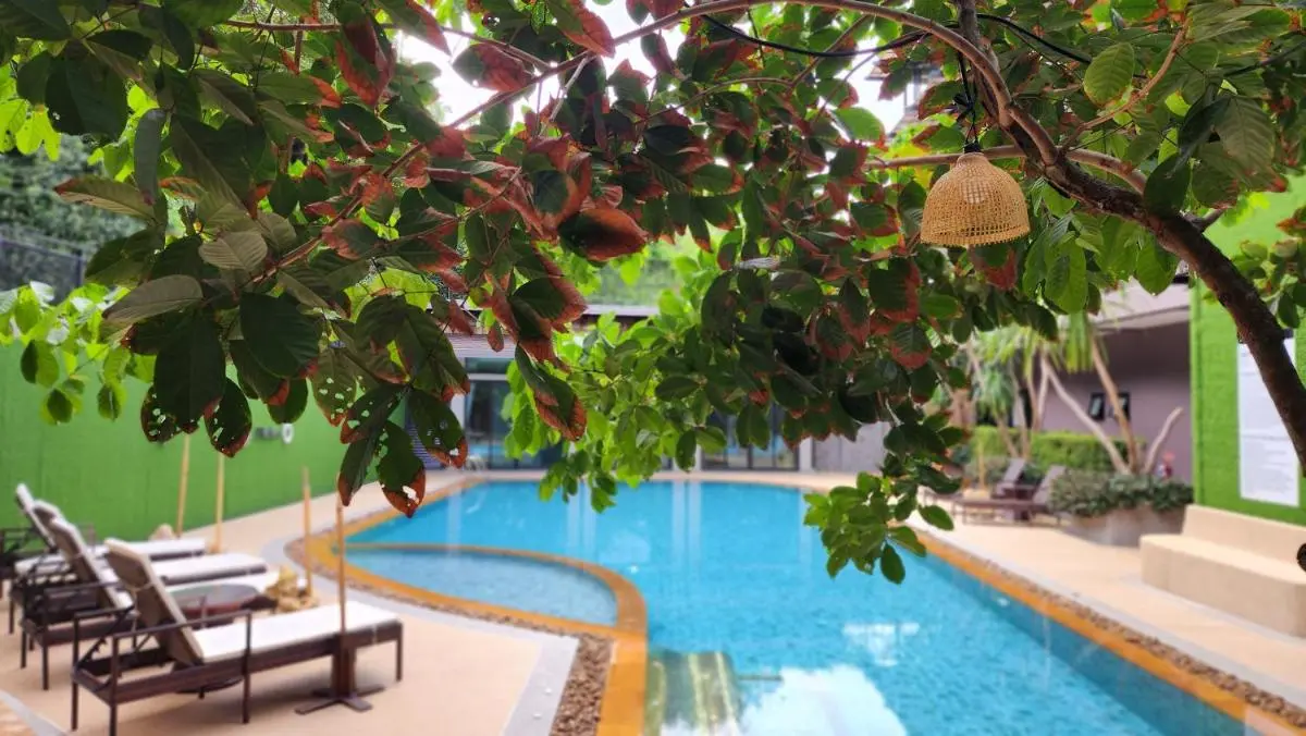 Outdoor Swimming Pool Area with Lounge Chairs and Natural Greenery in Ban Bo Rae