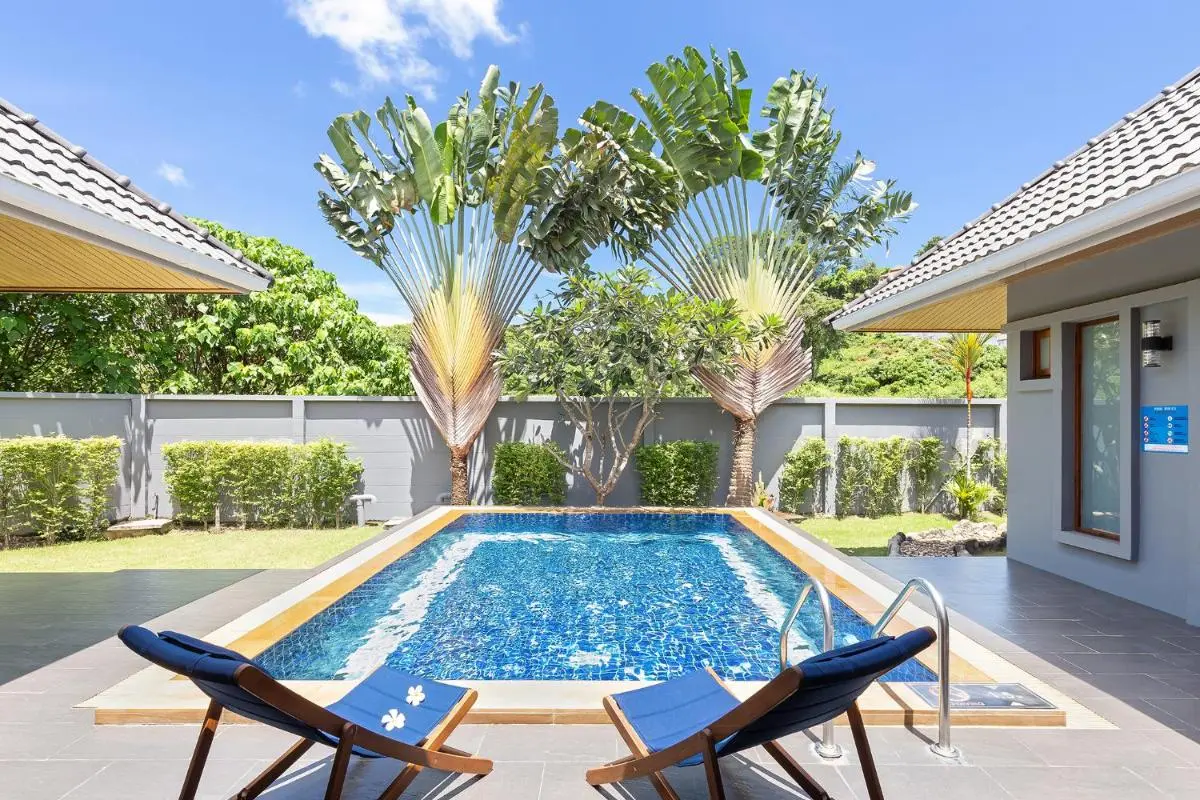 Outdoor Swimming Pool Area with Lounge Chairs and Tropical Plants at Rawai Beach