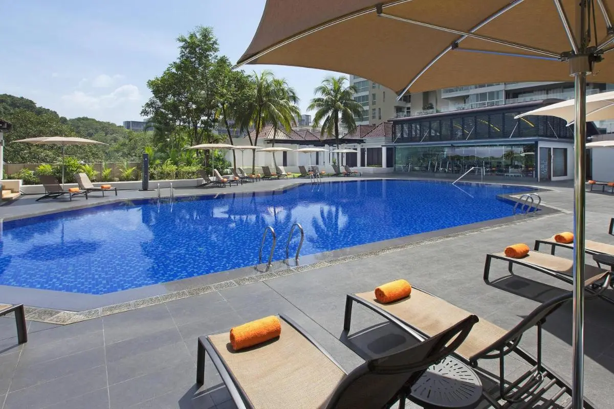 Outdoor Swimming Pool Area with Lounge Chairs and Umbrellas in Orchard